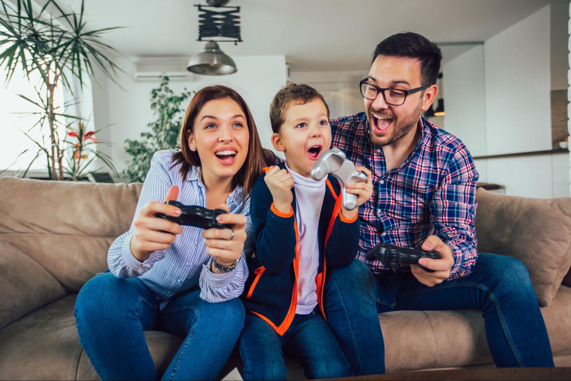 A family of three plays video games on consoles