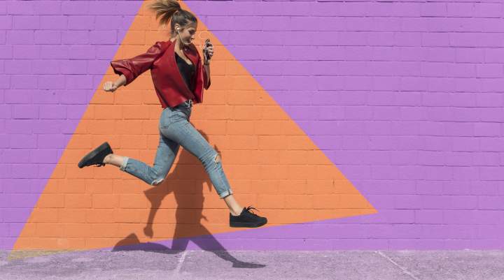A woman jumping in front of a brick wall