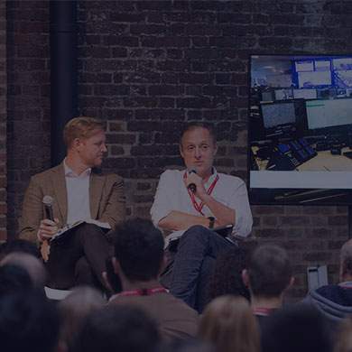 Stock photo of two men sitting in front of a plain brick wall