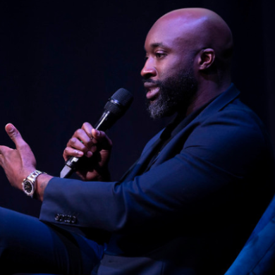 Man holding a mic while sitting in a chair
