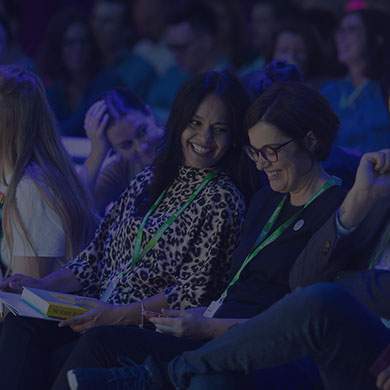 stock image of two women laughing together at a corporate event