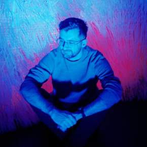 A picture of Sam Wray against a colourful background.