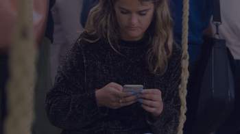 woman looking on her phone and sitting on a swing 