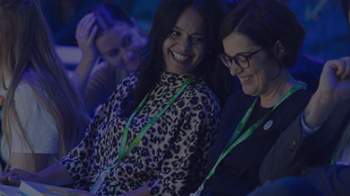 stock image of two women laughing together at a corporate event